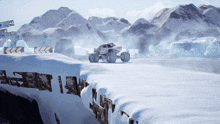 a monster truck is driving through a snowy area with mountains in the background