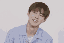 a young man in a blue shirt is smiling with his eyes closed .