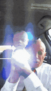 a man in a white shirt and tie holds a baby