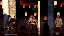 a group of people standing on a stage with a nbc logo in the corner