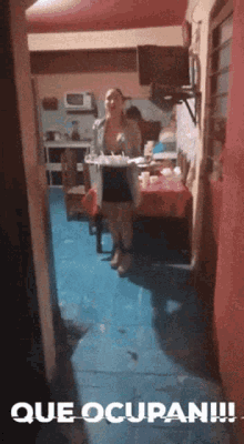 a woman standing in a kitchen with que ocupan written on the bottom of the image
