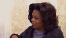 oprah winfrey is sitting on a couch making a funny face while looking at the camera .