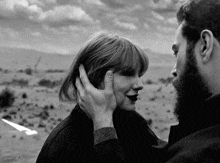 a man with a beard is touching a woman 's face