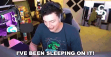 a man wearing headphones is sitting in front of a computer and says `` i 've been sleeping on it! ''
