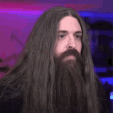a man with long hair and a beard is making a surprised face in a room .