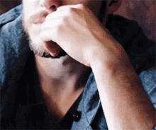 a man with a beard holds his hand to his mouth