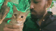 a man with a beard is holding a small orange cat