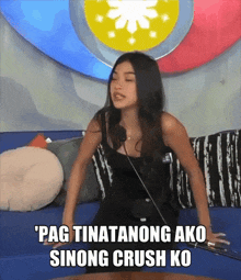 a woman is sitting on a couch with a microphone and a caption that says pag tinatanong ako sinong crush ko