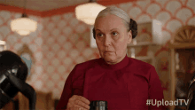 a woman in a red shirt is holding a cup of coffee with the hashtag #uploadtv