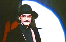 a man with a hat and glasses is standing in front of a white background