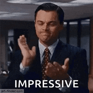 a man in a suit and tie is clapping his hands and making a face .