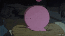 a pink cartoon character is sitting on a cushion in a dark room .