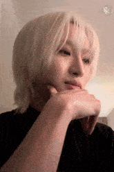 a close up of a person 's face with a black shirt and white hair
