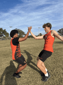two athletes high five each other in a field