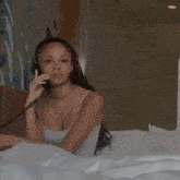 a woman laying on a bed talking on a telephone