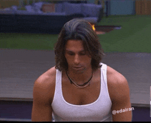 a man with long hair is wearing a white tank top with the hashtag @edaiiran on his arm