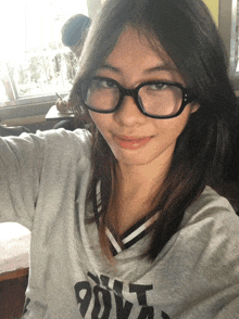 a girl wearing glasses and a shirt that says 90vt looks at the camera