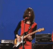 a man with a beard is playing an electric guitar and singing into a microphone .
