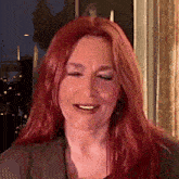 a woman with red hair is smiling with her eyes closed and her mouth open .