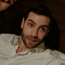 a man with a beard and a white shirt is smiling
