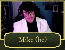 a man wearing glasses and headphones is sitting in a chair with the name mike ( he ) on a green background .