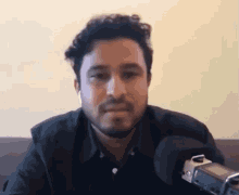 a man with a beard is talking into a microphone .