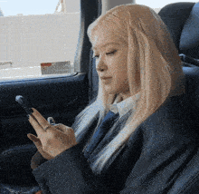 a woman in a suit and tie is looking at her phone