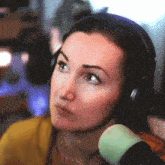 a woman wearing headphones and a yellow shirt is looking at the camera