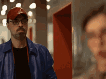 a man wearing glasses and a red hat is standing in a hallway