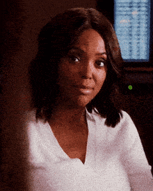 a woman in a white shirt is smiling in front of a green button