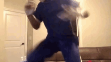 a man in a blue scrub top is jumping in a living room