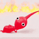 a red cartoon character with big eyes and a long tail is crawling on a white surface surrounded by flames .