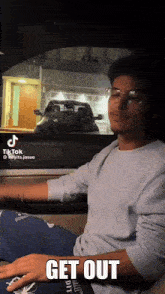 a man sitting in a car with the words get out written on the screen