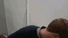 a man in a blue sweater sits in a bathroom
