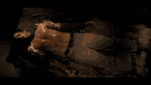 a shirtless man is laying on the ground with blood on his chest