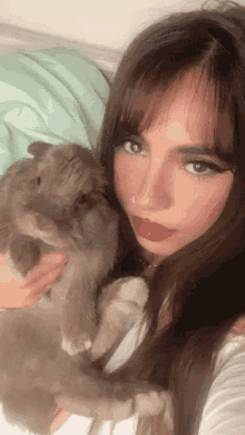 a woman with long hair is holding a rabbit in her arms
