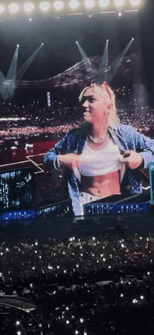 a woman taking off her shirt on a stage with a crowd watching