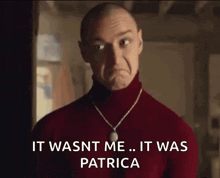 a bald man wearing a red turtleneck sweater and a necklace is making a sad face .