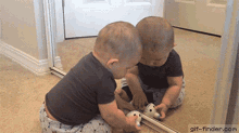 a baby is playing with a toy in front of a mirror with gif-finder.com written below it