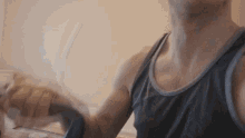 a man in a tank top is holding something in his hands
