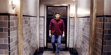 a man in a red shirt walks down a hallway