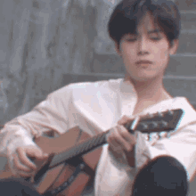 a man in a white shirt plays a guitar