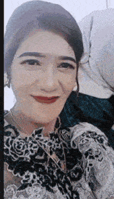 a woman in a black and white lace dress is smiling for a picture .