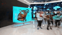 a blurred image of people walking in front of a large screen that says pika art on it