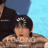 a man is sitting in front of a screen that says loading on it