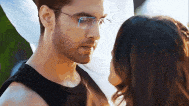 a man and a woman are looking at each other with glasses on .