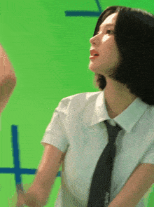 a woman in a white shirt and black tie is standing in front of a green background