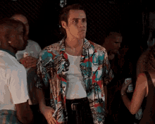 a man in a hawaiian shirt stands in a crowd of people