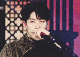 a close up of a person holding a microphone with a foreign language on the bottom left