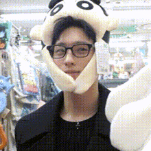 a man wearing a panda hat and glasses holds a stuffed animal
